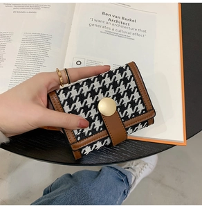Close-up of houndstress pattern wallet with brown leather trim and golden buckle clasp