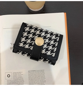 Close-up of houndstooth wallet with gold buckle and black faux leather edge detailing