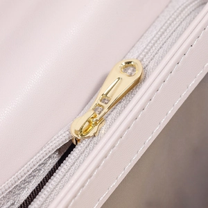 Détail de la fermeture éclair en métal doré et des coutures précises sur le portefeuille