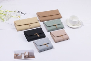 Dettaglio di portafogli in pelle PU con ciondoli a foglia e cuciture a reticolo