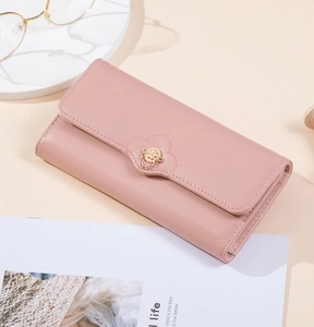 Detail of light pink long wallet featuring floral metal clasp and scalloped embroidery