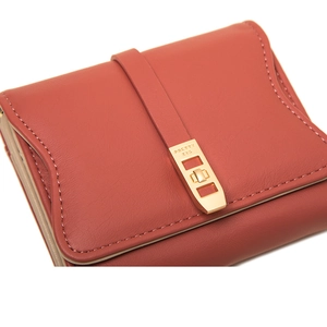 Macro shot of coral red leather wallet featuring a gold metal buckle and precision stitching