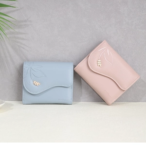 Close-up of trifold wallets with delicate leaf embroidery and metal hardware