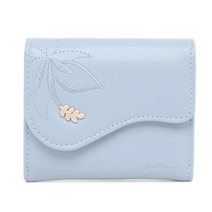Detail of light blue tri-fold wallet featuring leaf embroidery and golden leaf charm