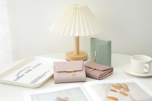 Detail of short tri-fold faux leather wallets with quilted pattern and leaf pendant charm