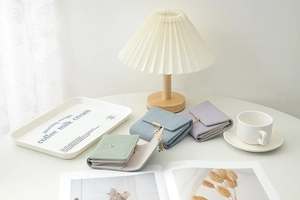 Close-up of quilted tri-fold wallets with leaf pendants in pastel green, blue, and purple