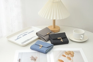 Short quilted wallets in grey and blue with leaf pendants and elegant metal clasps