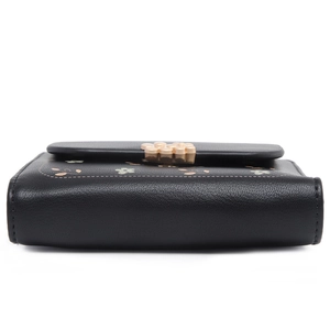 Detail of black pebbled leather wallet with floral print and gold flower metal clasp
