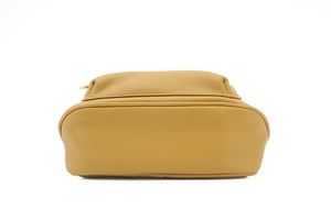 Vue macro de la base d'un sac en similicuir jaune moutarde avec grain de litchi texturé
