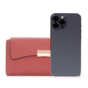 Portefeuille long en cuir corail avec boucle dorée présenté à côté d'un smartphone