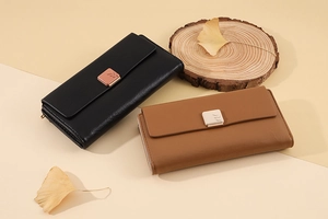 Close-up of minimalist long PU wallets in black and brown with leaf engraved hardware