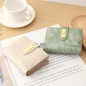 Detail view of beige and green PU leather wallets with elegant metal buckles on a magazine