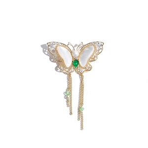 Detail of butterfly brooch with shell inlay, green zircon and hanging gold tassels