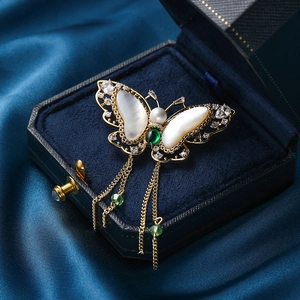 Elegant gold butterfly brooch with shell wings, green gems and dangling tassels