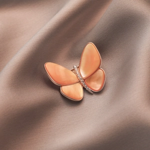 Elegante broche de mariposa con nácar rosa y circonitas sobre satén color champán