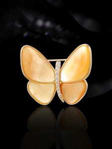 Vista macro de broche de mariposa dorado con alas de nácar amarillo y circonitas