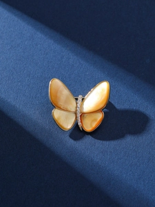 Detalle macro de broche de mariposa dorada con alas de nácar naranja y cristales brillantes