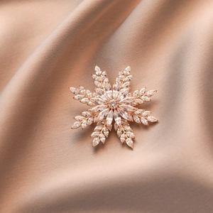 Broche flocon de neige rotative en or rose avec cristaux marquise sur soie champagne