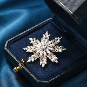Broche flocon de neige rotative dorée avec zircons dans un écrin en velours bleu