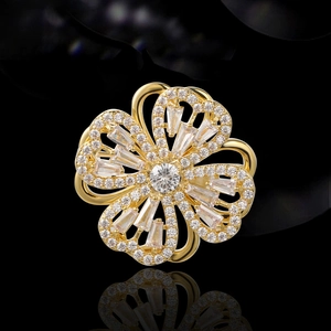Goldene Blumenbrosche mit drehbaren Herz-Blütenblättern und Kristallen auf schwarzem Grund