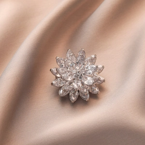 Luxurious silver lotus flower brooch with sparkling marquise crystals on champagne silk