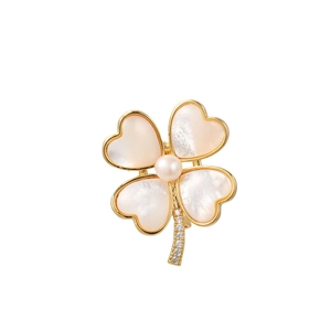 Détail macro de broche trèfle à quatre feuilles avec pétales en nacre et bords dorés
