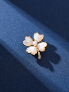 Vue rapprochée d'une broche trèfle avec perle d'eau douce et nacre blanche sur métal doré