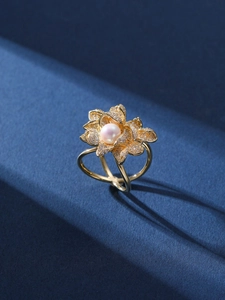 Detail of gold lotus brooch with micro-pave zircons and a natural pearl on velvet