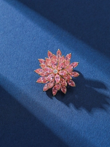 Detail view of pink zircon flower brooch with rotatable design on blue background