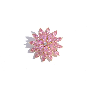 Macro detail of rotating pink zircon flower brooch with layered petals and gold-plated base