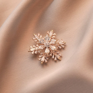 Broche flocon de neige en or rose élégante avec zircons sur un fond de satin de champagne