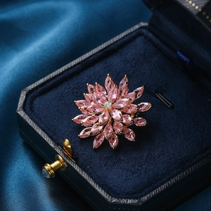 Detailed macro view of a pink zircon floral brooch set in a luxury velvet jewelry box