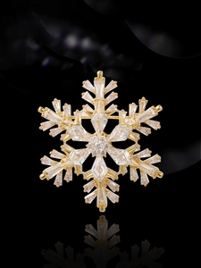 Gros plan d'une broche flocon dorée avec zircons sur une surface en miroir noir
