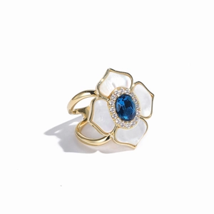 Detail of camellia ring with white shell petals and a blue gemstone centerpiece