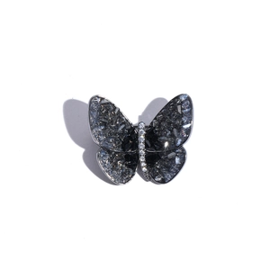 Macro detail of butterfly brooch with dark crystals and white zircon body on silver base