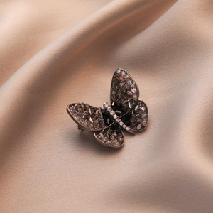 Elegant butterfly brooch with dark grey crystals on champagne silk background