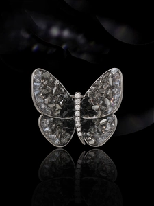 Close-up of elegant butterfly brooch with grey crystals and white zircons on black base