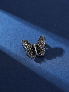 Macro shot of butterfly brooch with dark crystals, white zircons and deep side shadows