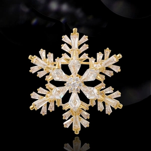 Élégante broche flocon de neige rotative dorée avec cristaux et reflet sur fond noir