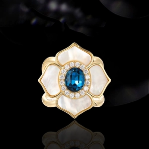 Elegant floral silk scarf ring with shell petals and deep blue stone on black background