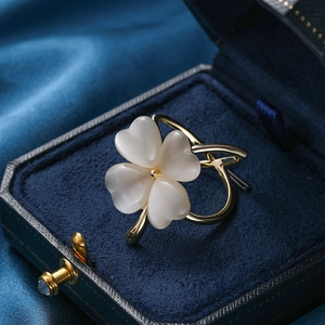 Broche trèfle doré avec pierres œil de chat blanches sur un fond en velours bleu