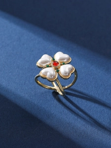 Macro detail of a vintage clover ring with heart pearls and a red center stone