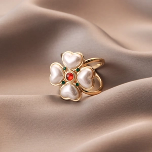 Vintage gold clover ring with heart-shaped pearls and red center stone on brown silk