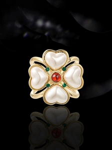 Detail of vintage clover brooch with heart-shaped pearls and vibrant gemstones inlay