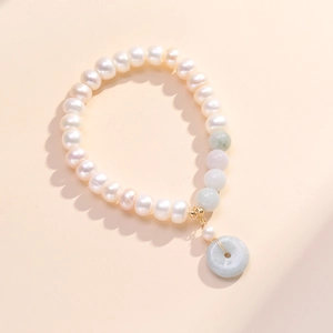 Elegant freshwater pearl and emerald bracelet with golden peace buckle pendant detail