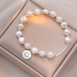 Detail of baroque pearl bracelet with silver smile charm in a premium jewelry gift box
