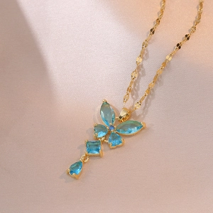 Collier papillon doré élégant avec zircons bleus sur fond de soie rose doux
