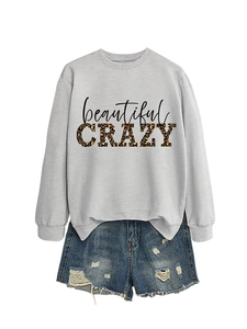Flat lay of grey sweatshirt with leopard print CRAZY text and ripped denim shorts