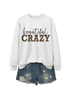 Flat lay of a grey sweatshirt featuring crazy leopard print text and denim shorts