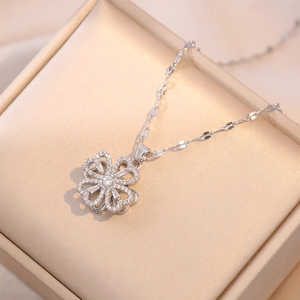Macro shot of a silver clover necklace with zircon heart petals on a jewelry gift box